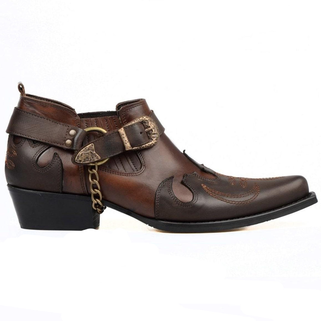 A brown leather ankle boot with a buckle, chain, and western-inspired detailing.
